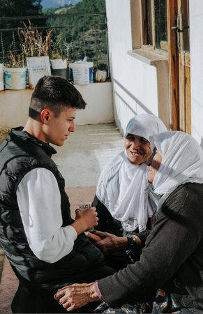 A young man talking with two older women outside